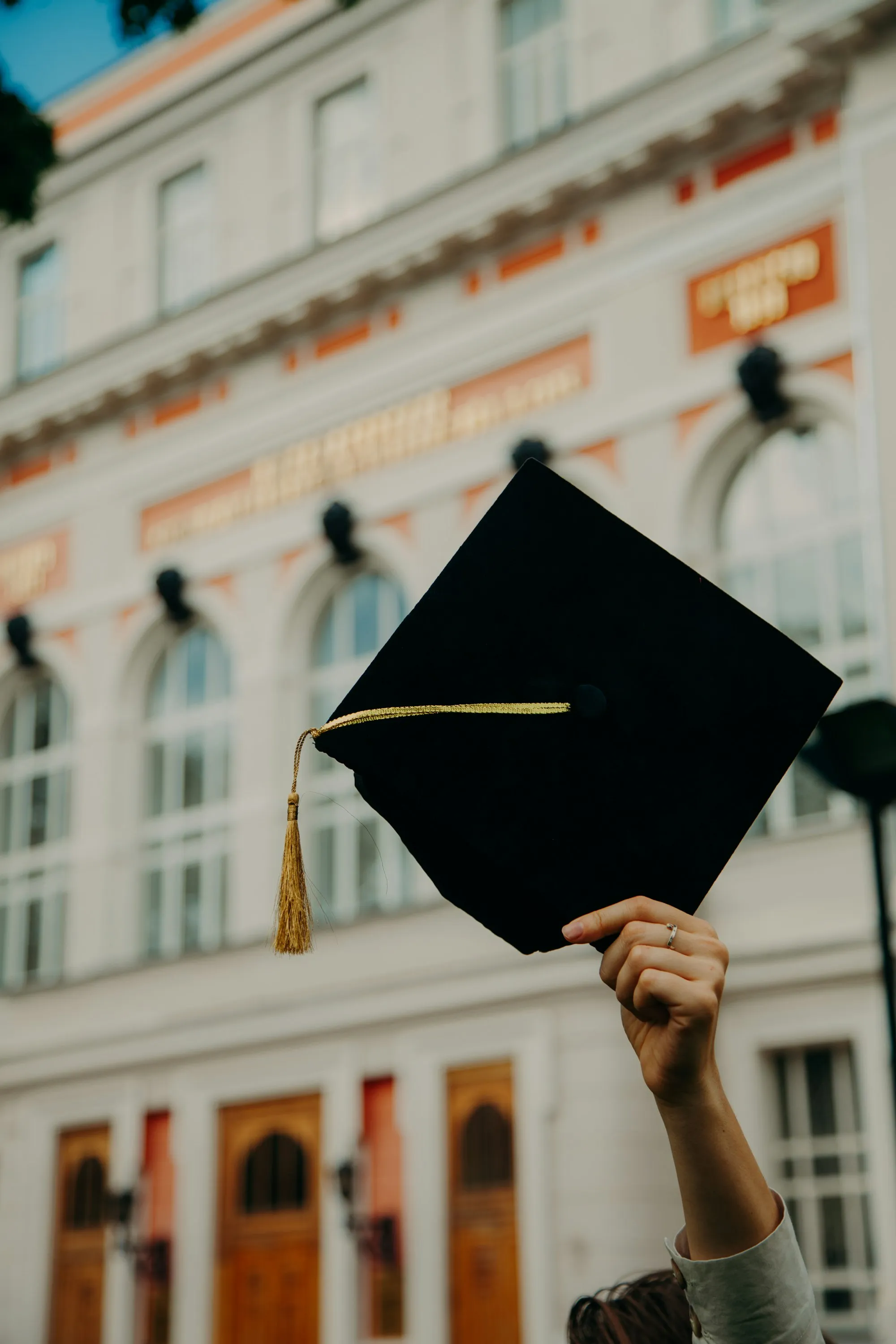 A graduation cap held up in front of a historic building