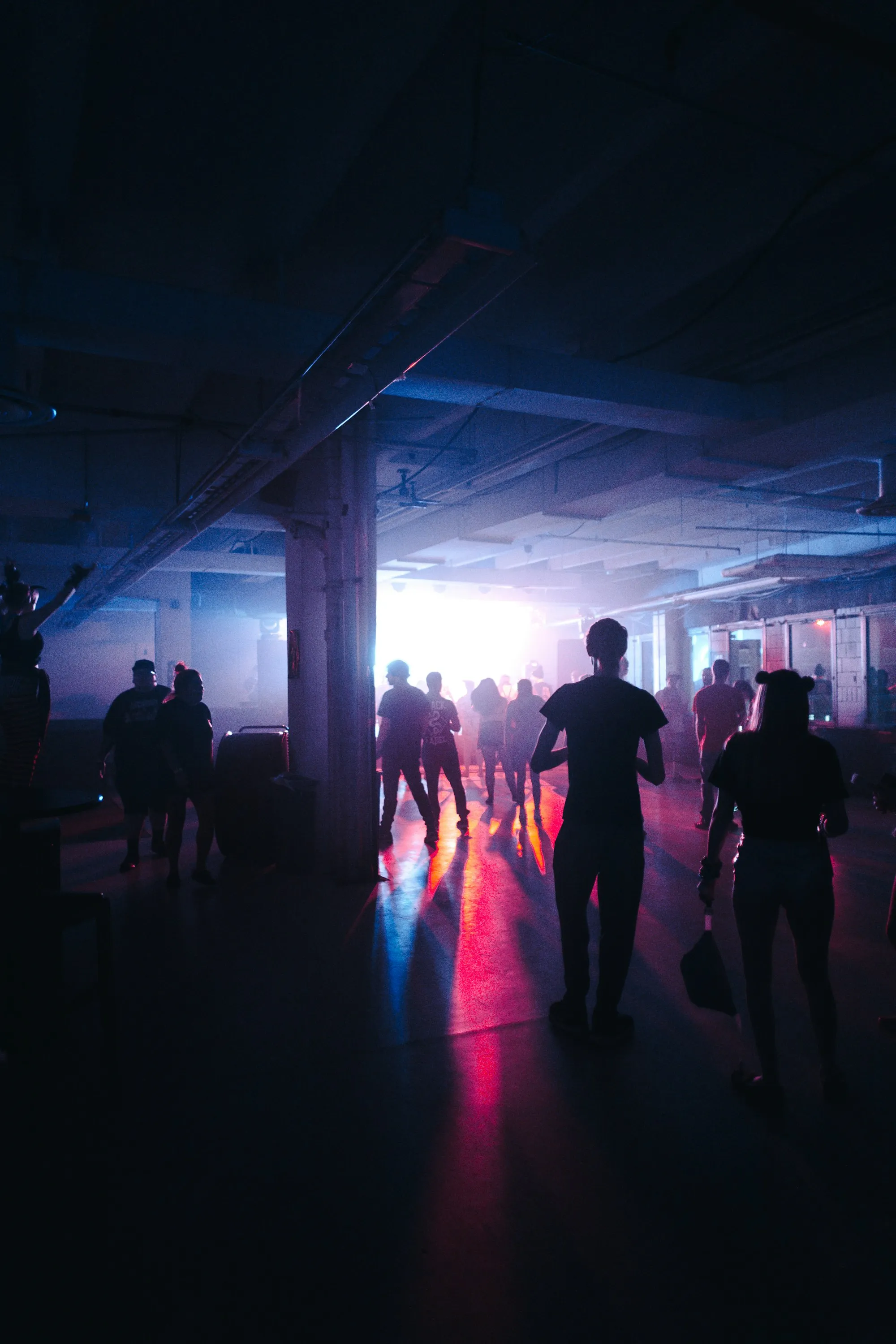 Dancers silhouetted under colored lights in a large hall