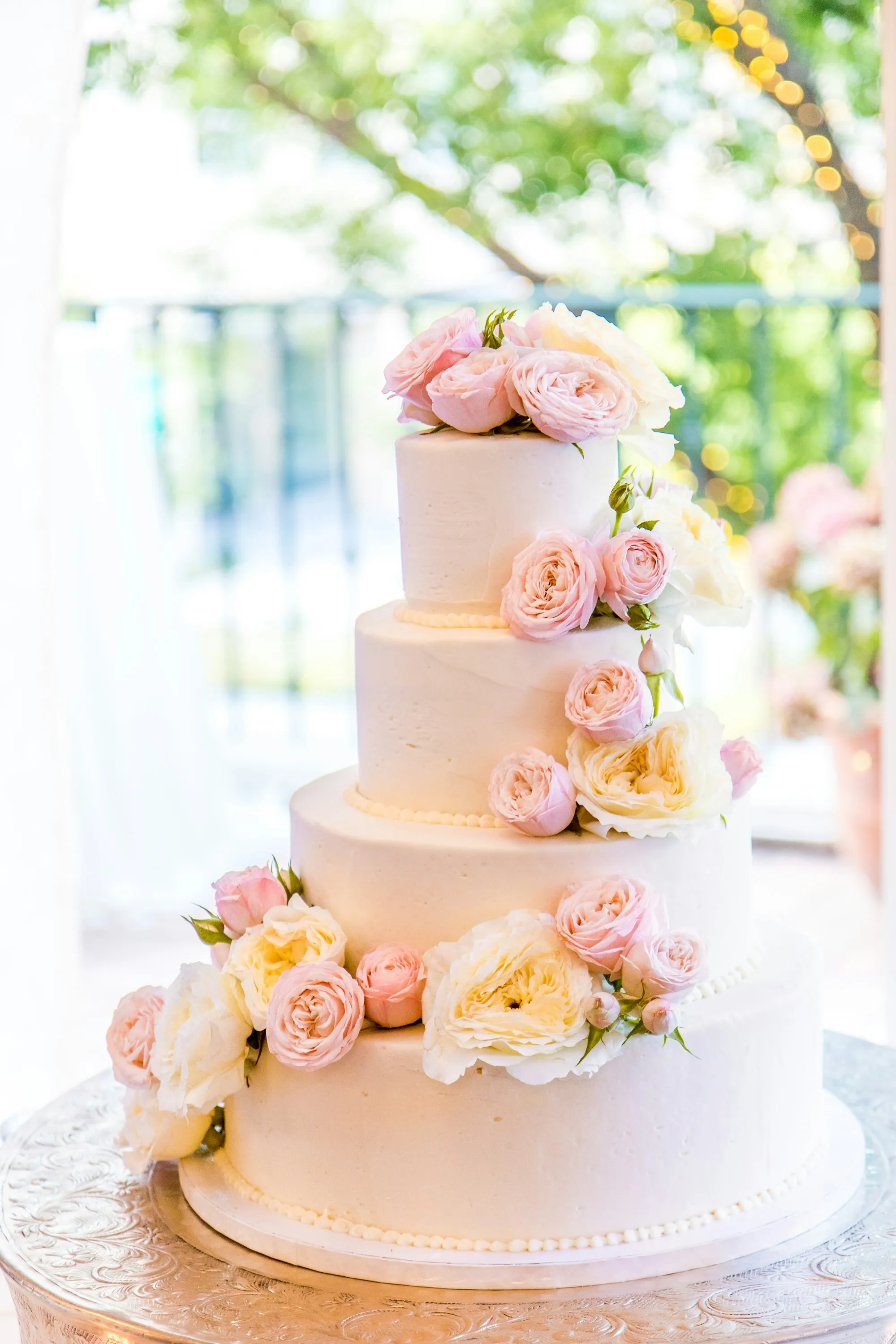 A tiered white cake decorated with blush and ivory roses