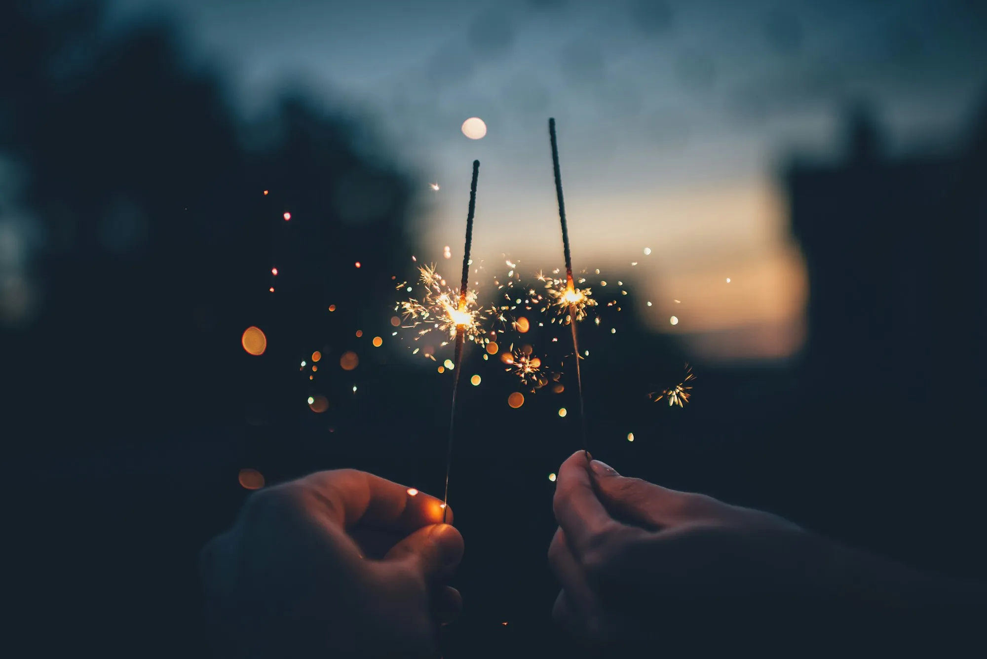 Two sparklers glowing against the evening sky