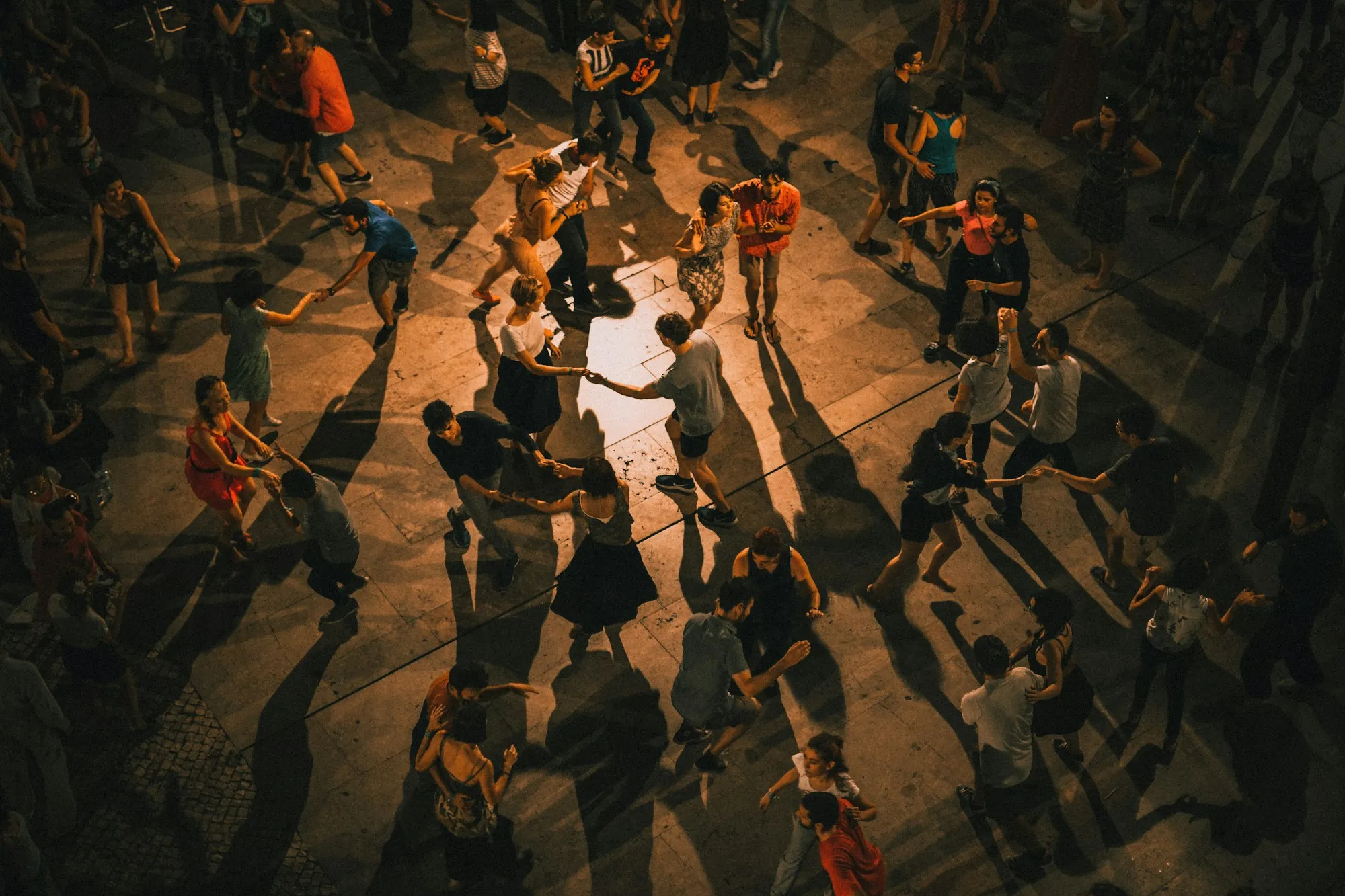 Guests dancing on a crowded floor in warm light, seen from above